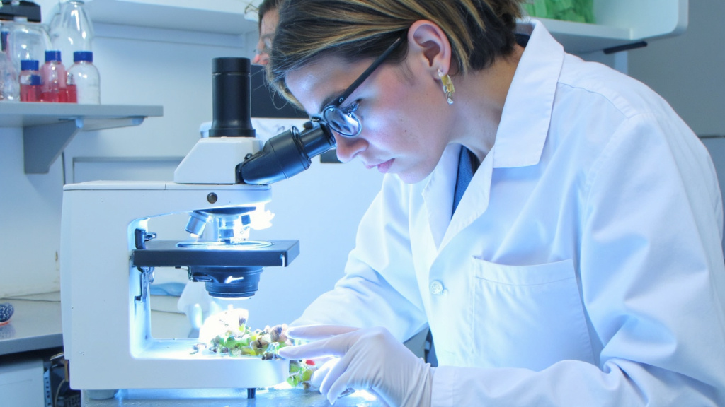 Scientist Examining Eco-Friendly Magnet Materials Scientist in lab coat examining eco-friendly magnet materials under microscope, recycled components visible