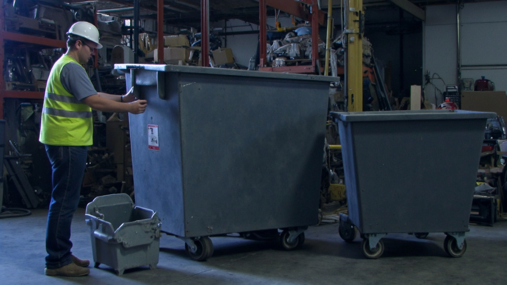 Comparison of Scrap Metal Bins in Warehouse Person comparing different sizes of scrap metal bins in a warehouse, examining features and capacities