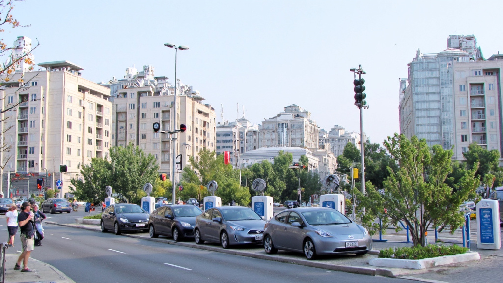 Futuristic Cityscape with Magnetic Cooling Systems Futuristic cityscape showcasing magnetic cooling systems on buildings and electric vehicle charging stations.
